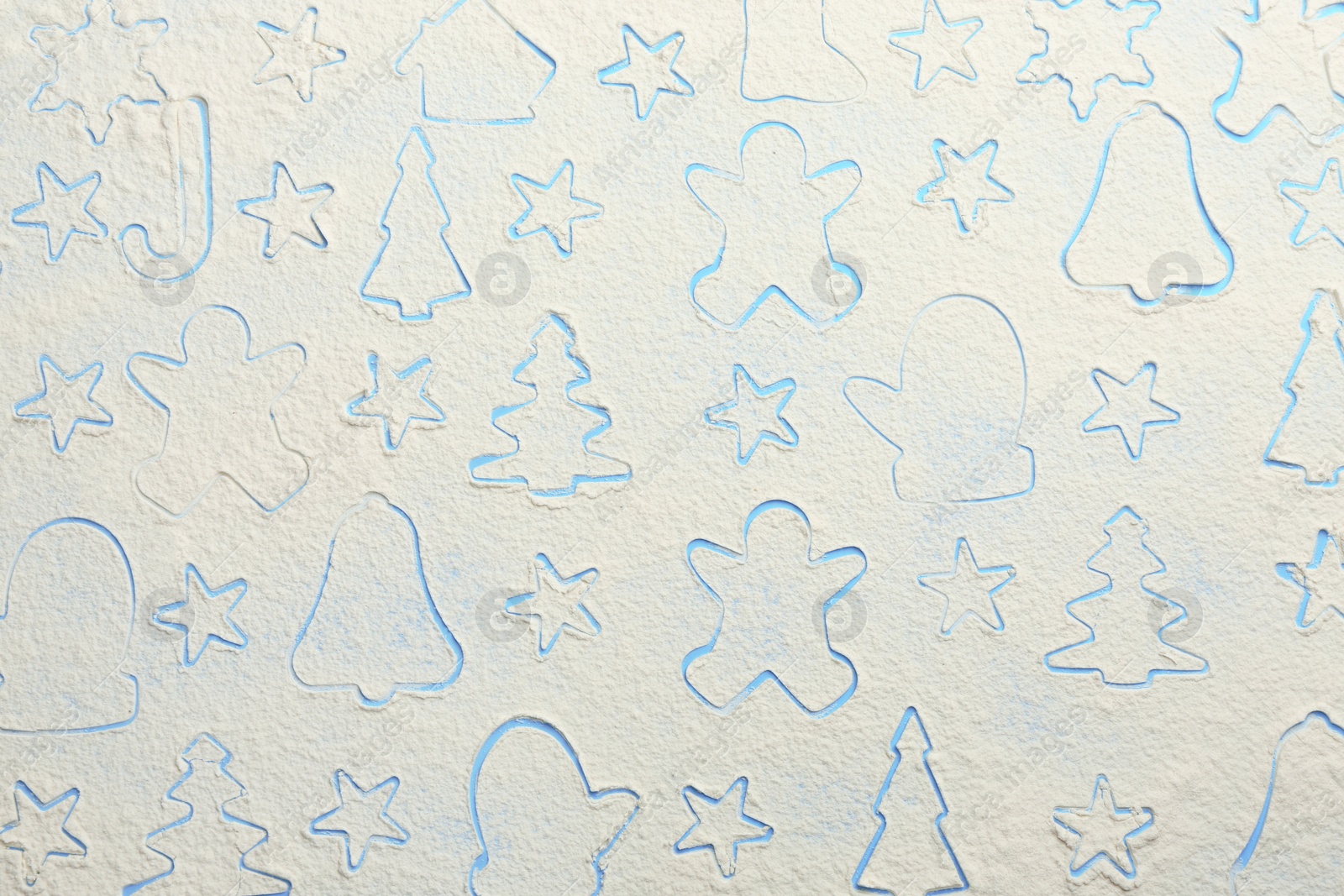 Photo of Different Christmas cookie shapes made of flour on light blue background, top view