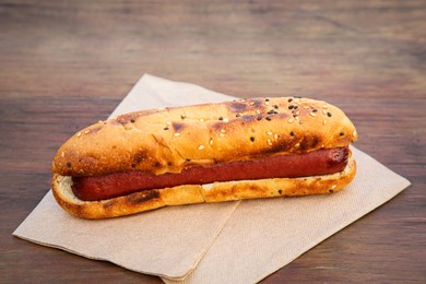 Photo of Fresh tasty hot dog on wooden table, closeup