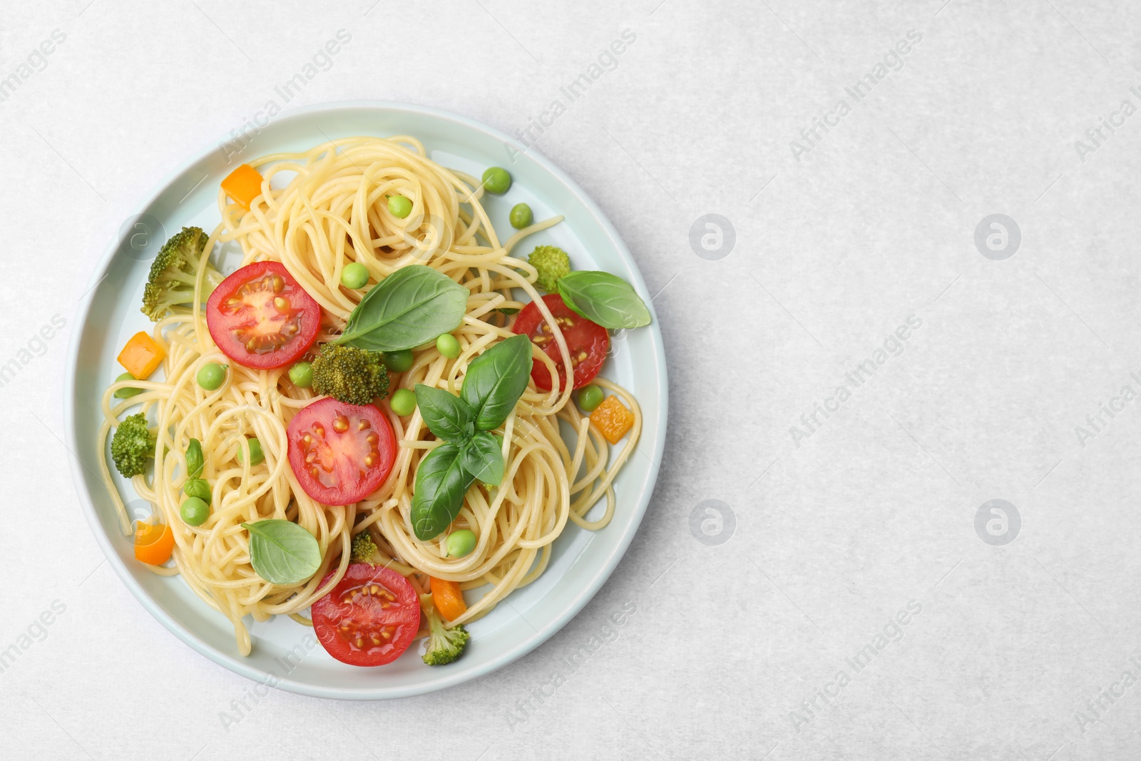 Photo of Plate of delicious pasta primavera on light gray table, top view. Space for text