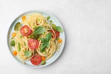 Plate of delicious pasta primavera on light gray table, top view. Space for text