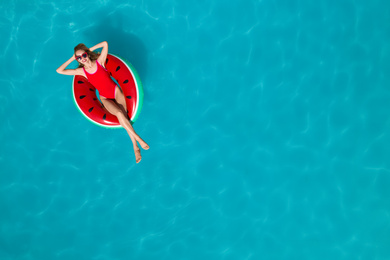 Image of Young happy woman with inflatable ring in swimming pool, top view and space for text. Summer vacation