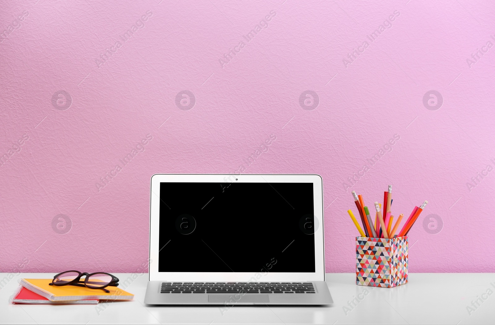 Photo of Modern laptop on table against color wall. Mock up with space for text