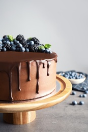 Photo of Fresh delicious homemade chocolate cake with berries on table against gray background