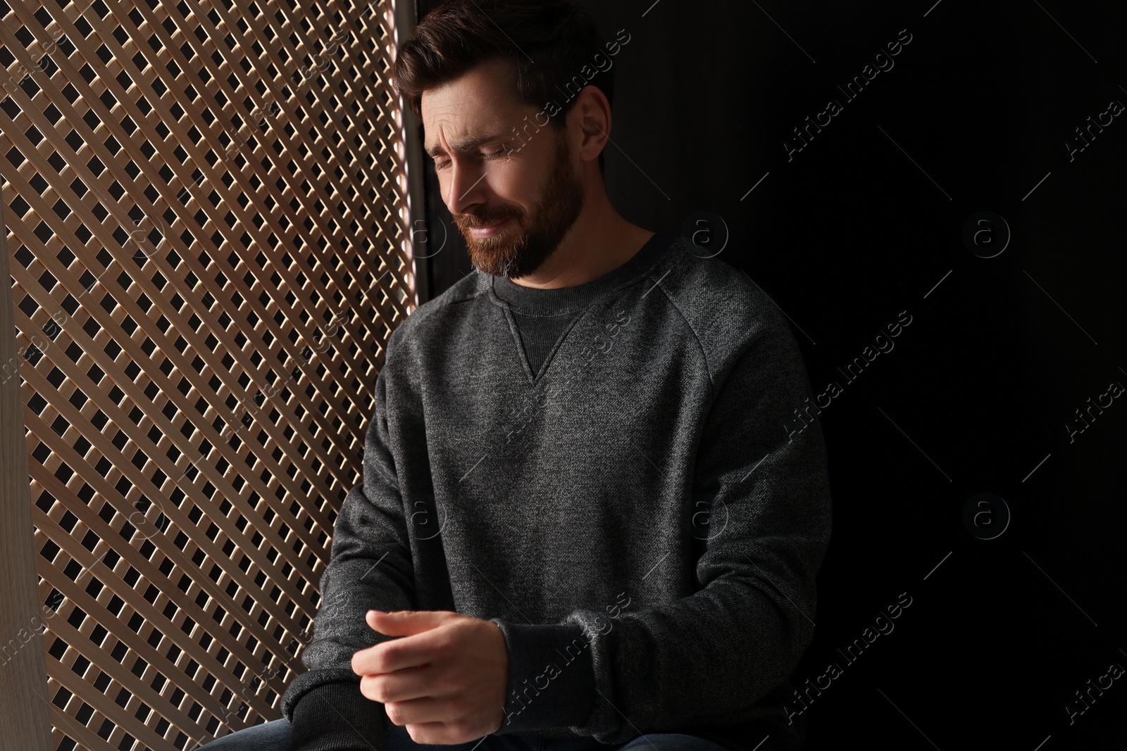 Photo of Upset man talking to priest during confession in booth