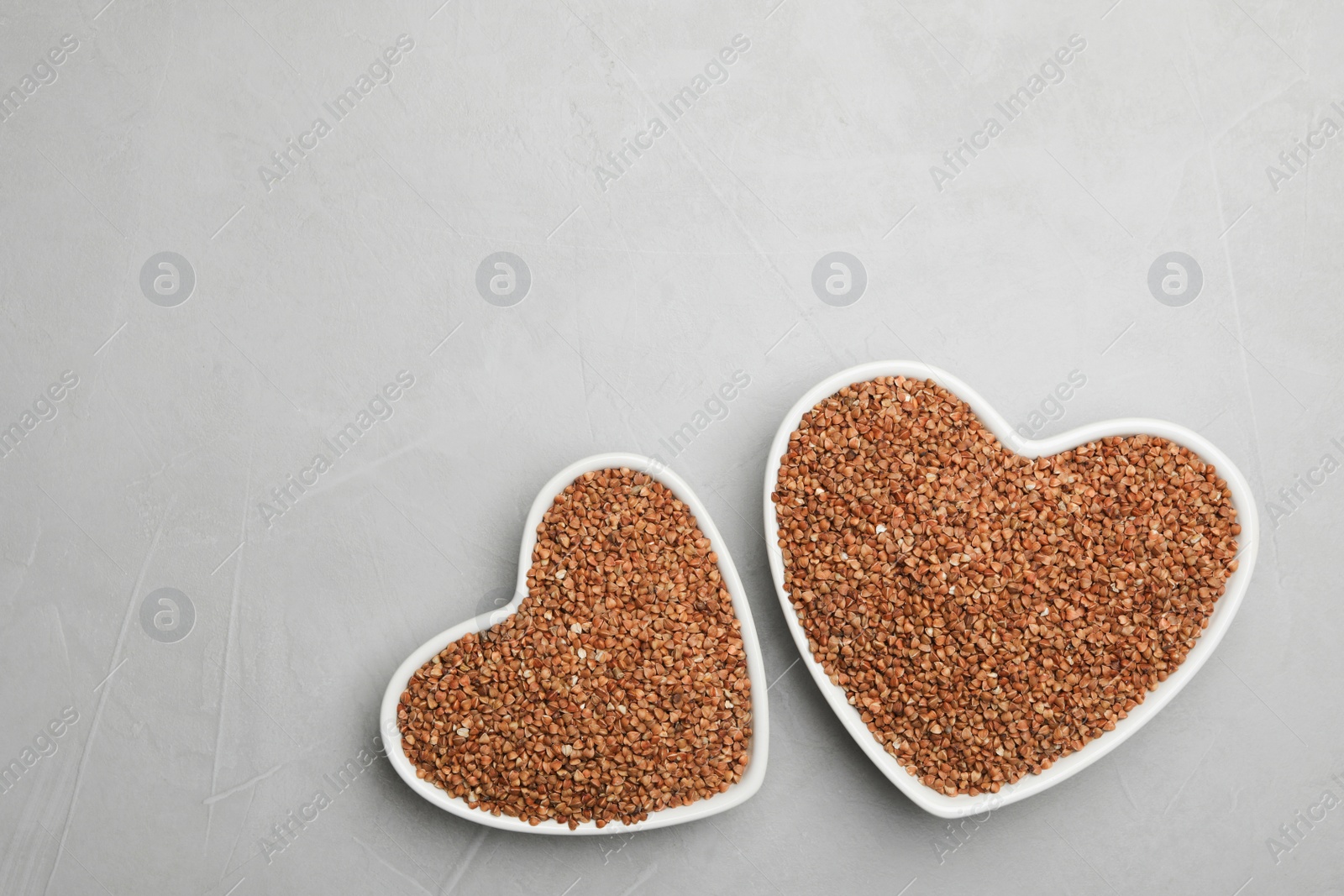 Photo of Buckwheat grains on grey table, flat lay. Space for text