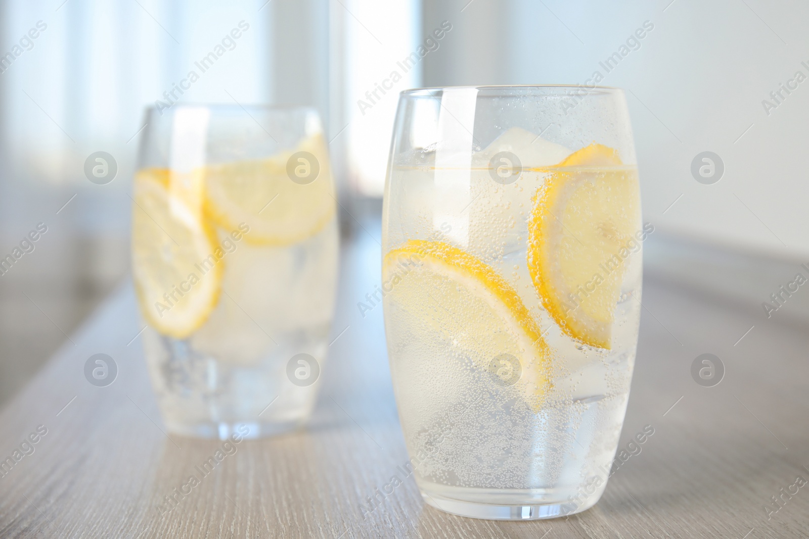 Photo of Soda water with lemon slices and ice cubes on wooden table indoors. Space for text