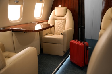 Image of Airplane cabin with red suitcase. Air travel