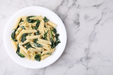 Tasty pasta with spinach and sauce on white marble table, top view. Space for text