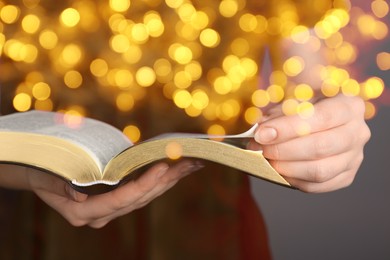 Woman reading Bible, closeup view. Bokeh effect