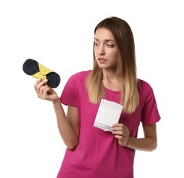 Photo of Confused young woman with disposable and reusable cloth menstrual pads on white background