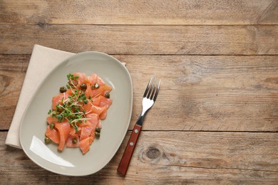 Photo of Delicious salmon carpaccio served on wooden table, flat lay. Space for text