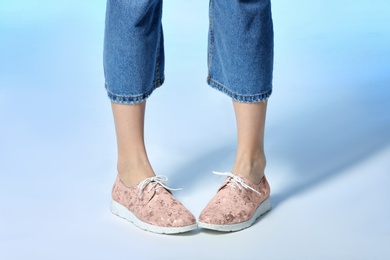 Woman in stylish shoes on color background, closeup