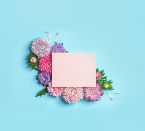 Photo of Beautiful aster flowers with sheet of paper on color background, top view. Space for text