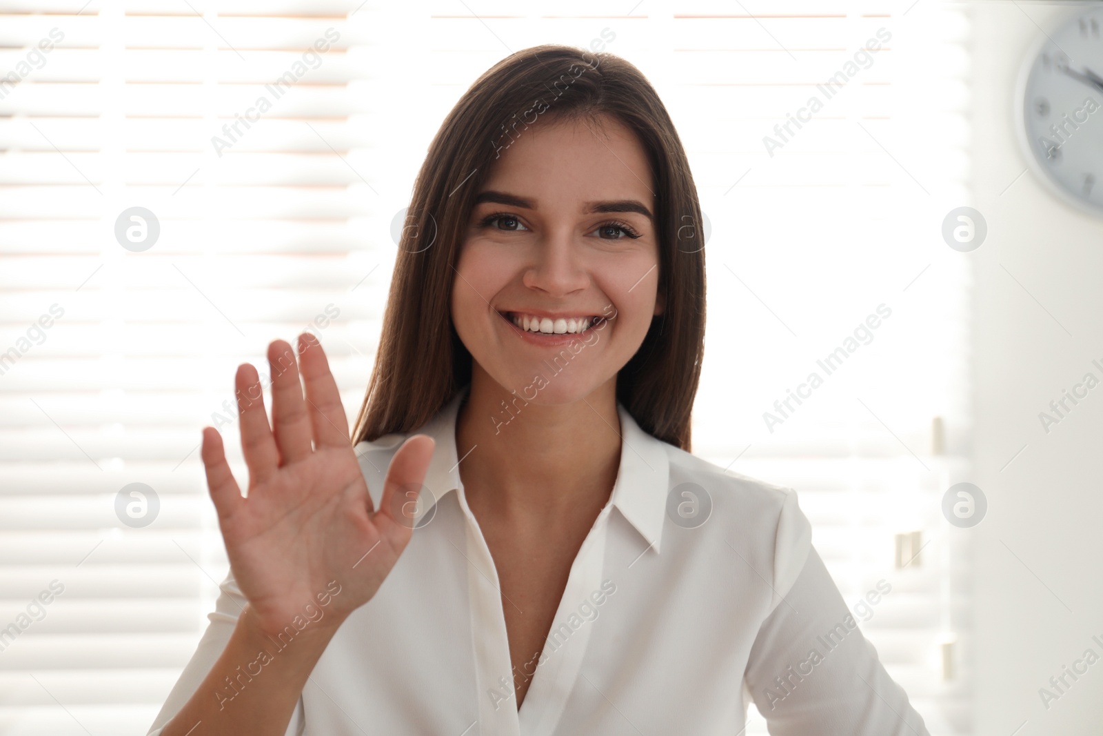 Photo of Young woman talking to her coworkers through video conference in office, view from webcam