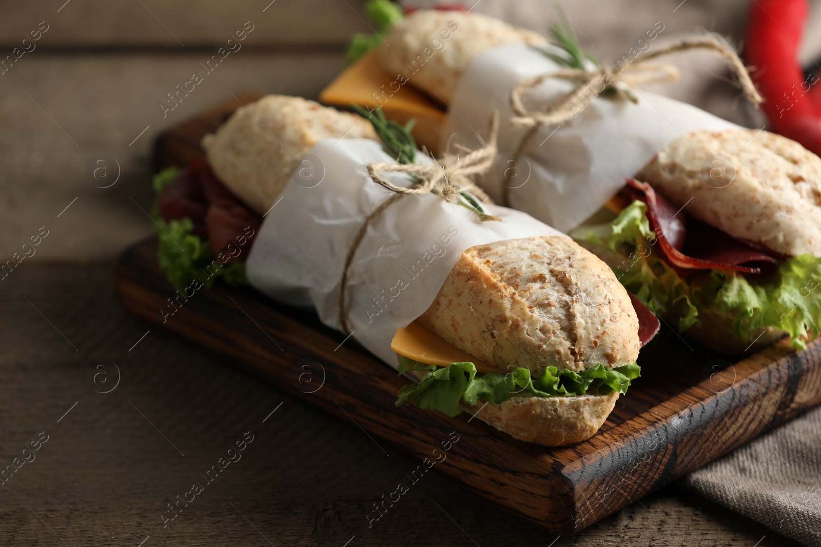 Photo of Delicious sandwiches with bresaola, lettuce and cheese on wooden table, closeup