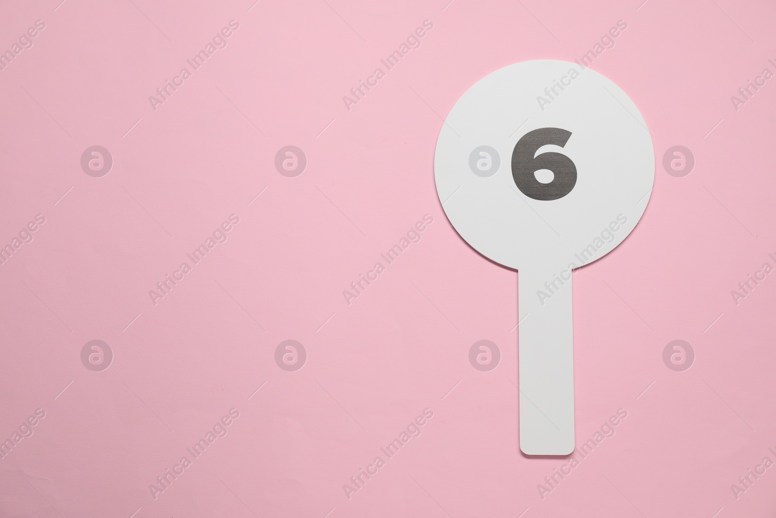 Photo of Auction paddle with number 6 on pink background, top view. Space for text