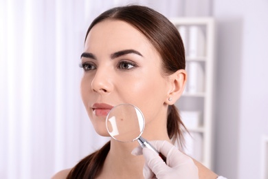 Dermatologist examining patient with magnifying glass in clinic