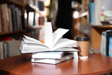 Books and cup of coffee on table in library