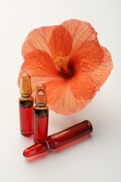 Photo of Skincare ampoules and hibiscus flower on white background