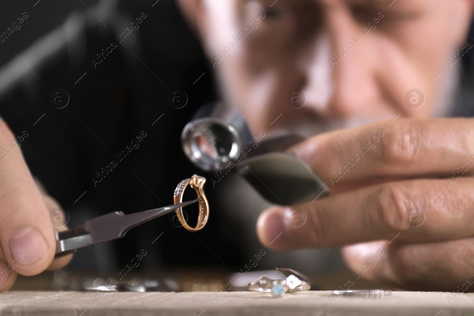 Photo of Male jeweler evaluating diamond ring in workshop, closeup view