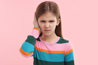 Photo of Hearing problem. Little girl suffering from ear pain on pink background