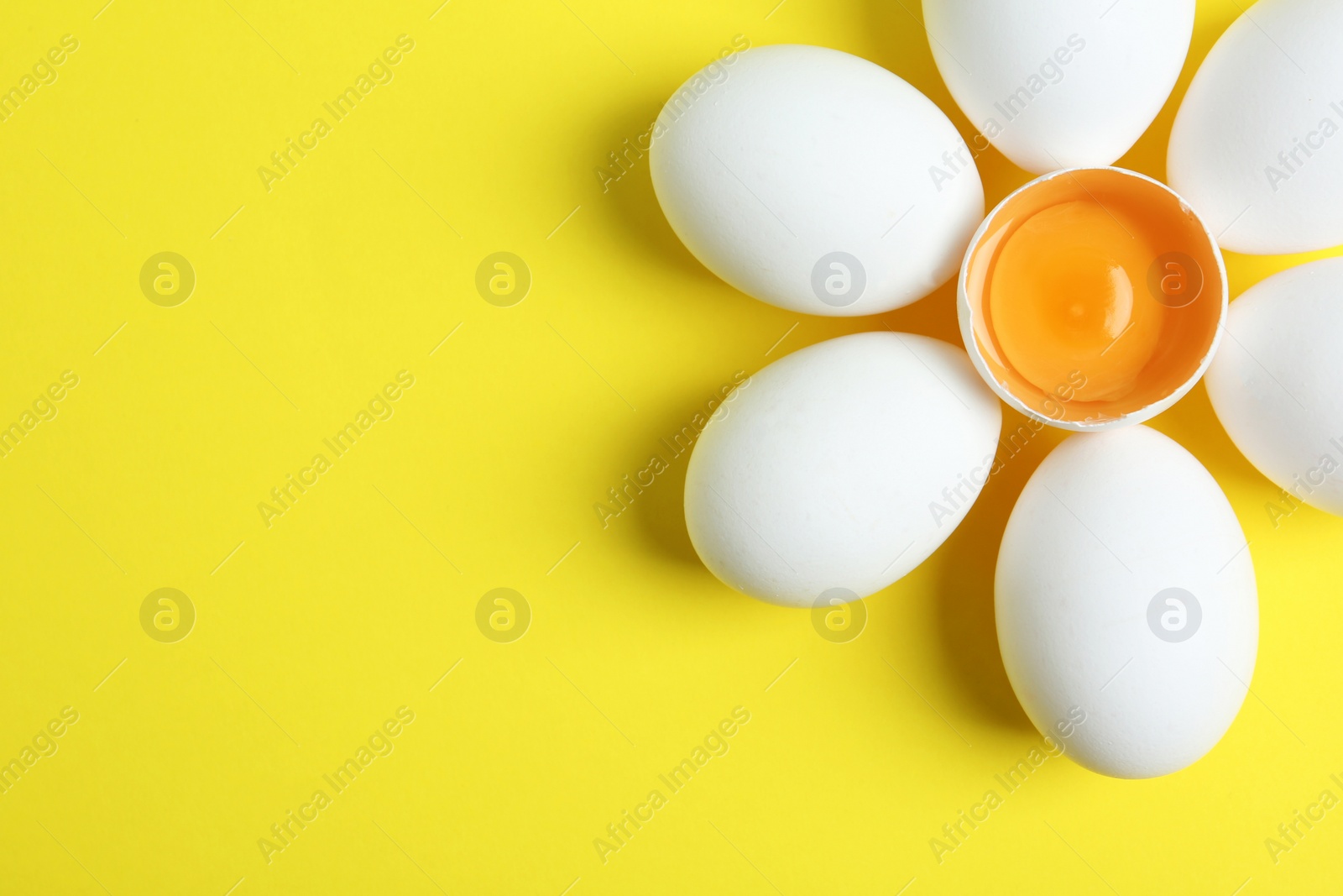 Photo of Fresh raw chicken eggs on yellow background, flat lay. Space for text