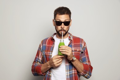 Man drinking delicious juice on grey background