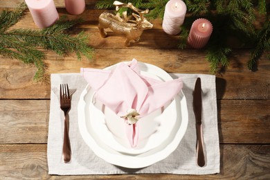 Photo of Stylish table setting with pink fabric napkin, beautiful decorative ring and festive decor on wooden background, flat lay