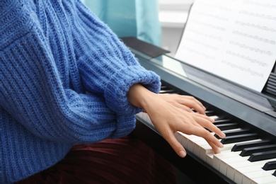 Photo of Young woman playing piano at home, closeup