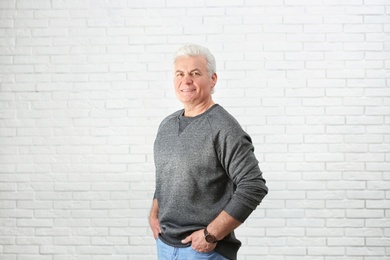 Photo of Portrait of handsome mature man near brick wall