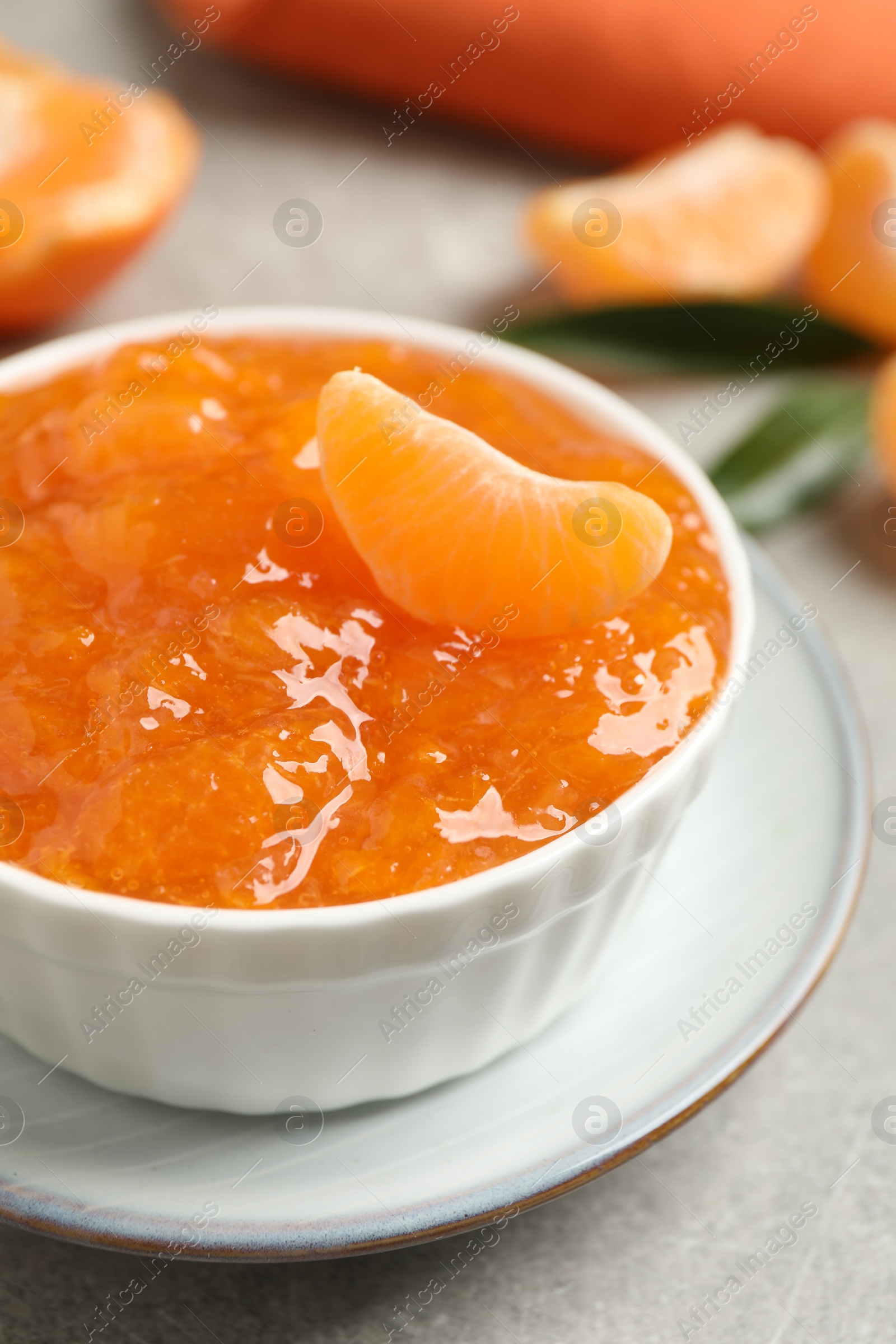 Photo of Delicious tangerine jam on light grey table, closeup