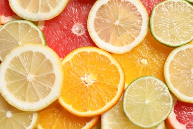 Photo of Different sliced citrus fruits as background, top view