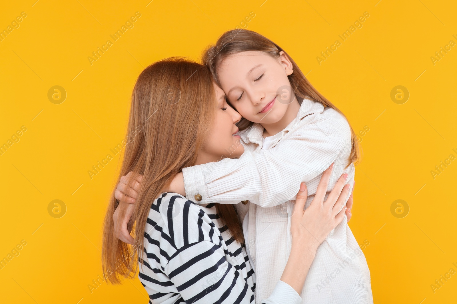 Photo of Portrait of happy mother and her cute daughter on orange background