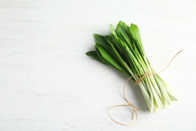 Bunch of wild garlic or ramson on white wooden table, top view with space for text