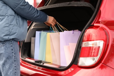 Photo of Woman putting shopping bags in car outdoors, closeup