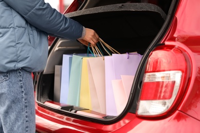 Woman putting shopping bags in car outdoors, closeup