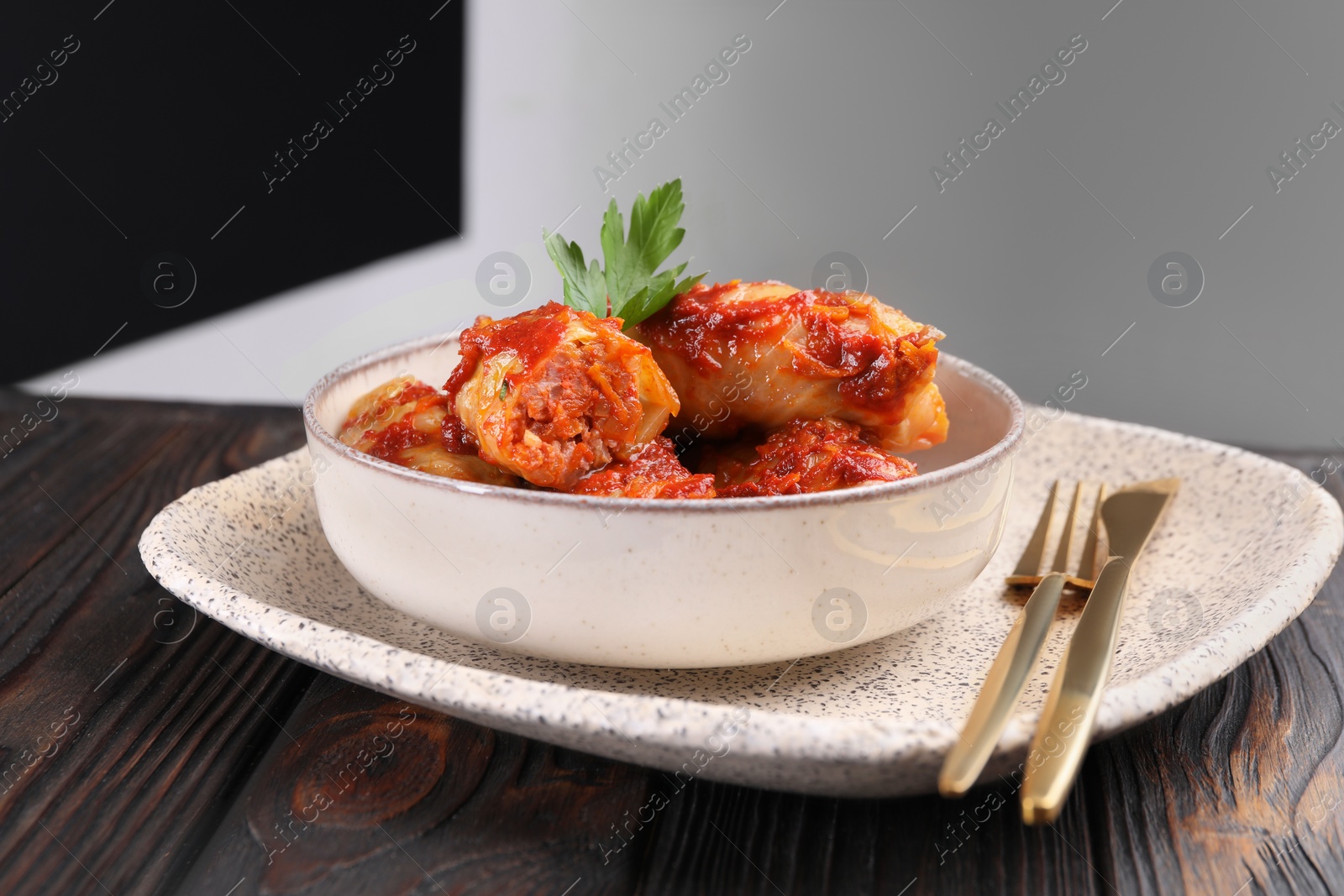 Photo of Delicious stuffed cabbage rolls cooked with tomato sauce on wooden table, closeup