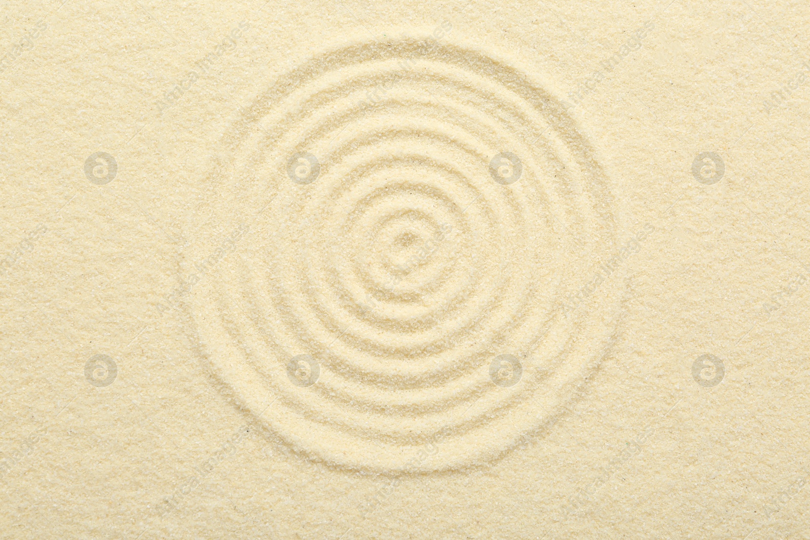 Photo of Zen rock garden. Circle pattern on beige sand, top view