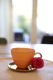 Photo of Cup of hot drink and red rose on table indoors. Space for text