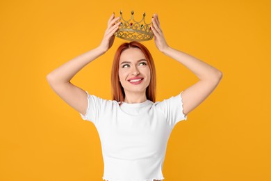 Photo of Beautiful young woman with golden crown on orange background