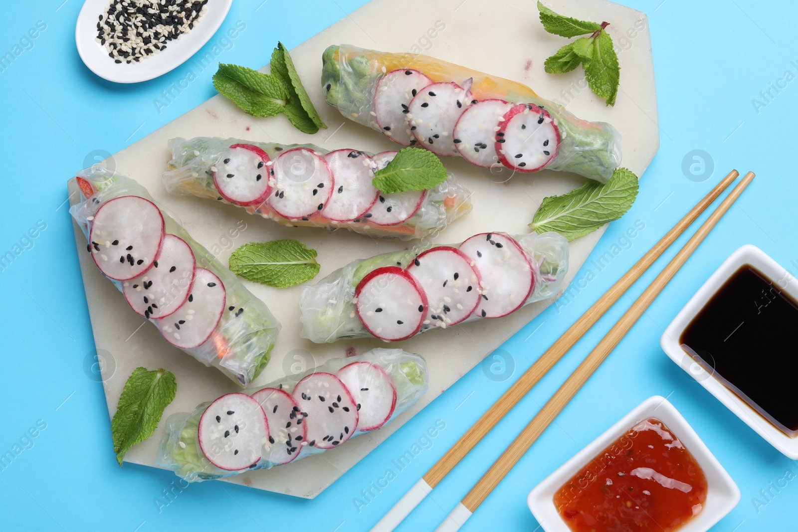 Photo of Delicious spring rolls served on light blue background, flat lay