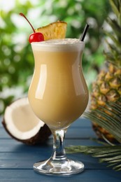 Photo of Tasty Pina Colada cocktail and ingredients on light blue wooden table