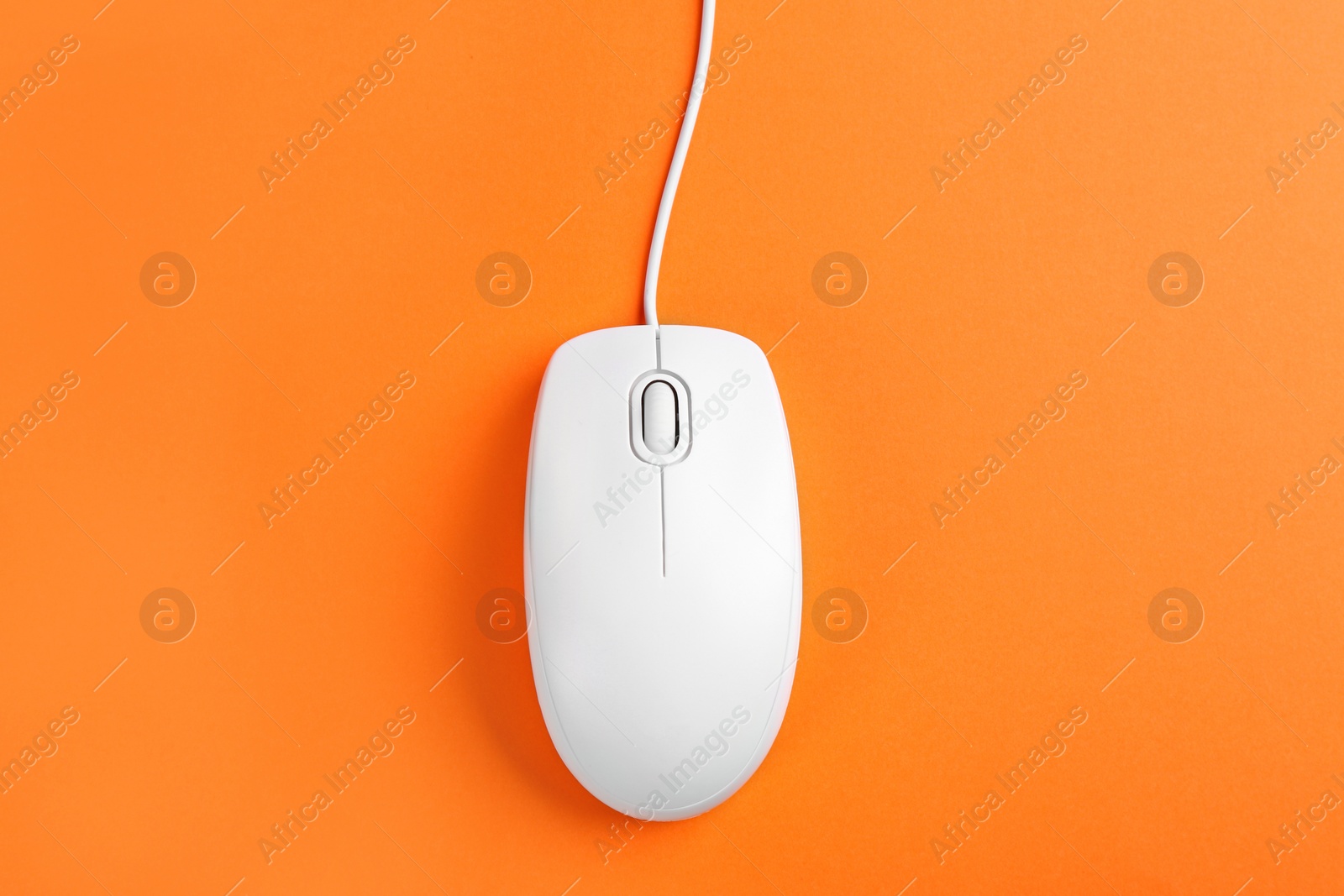 Photo of Modern wired optical mouse on orange background, top view
