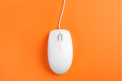 Modern wired optical mouse on orange background, top view