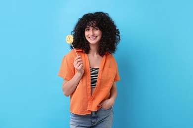 Beautiful woman with lollipop on light blue background