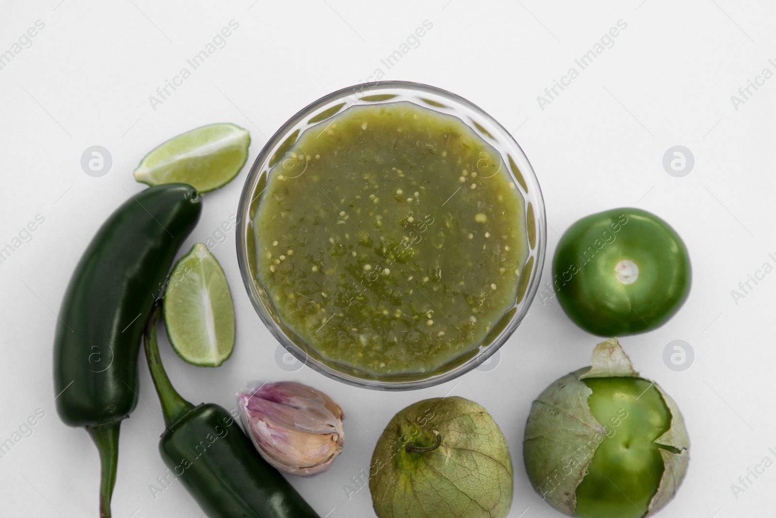 Photo of Tasty salsa sauce and ingredients on white background, top view