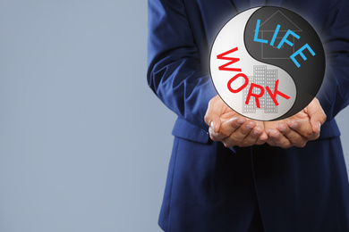 Businessman showing balance between life and work on grey background, closeup