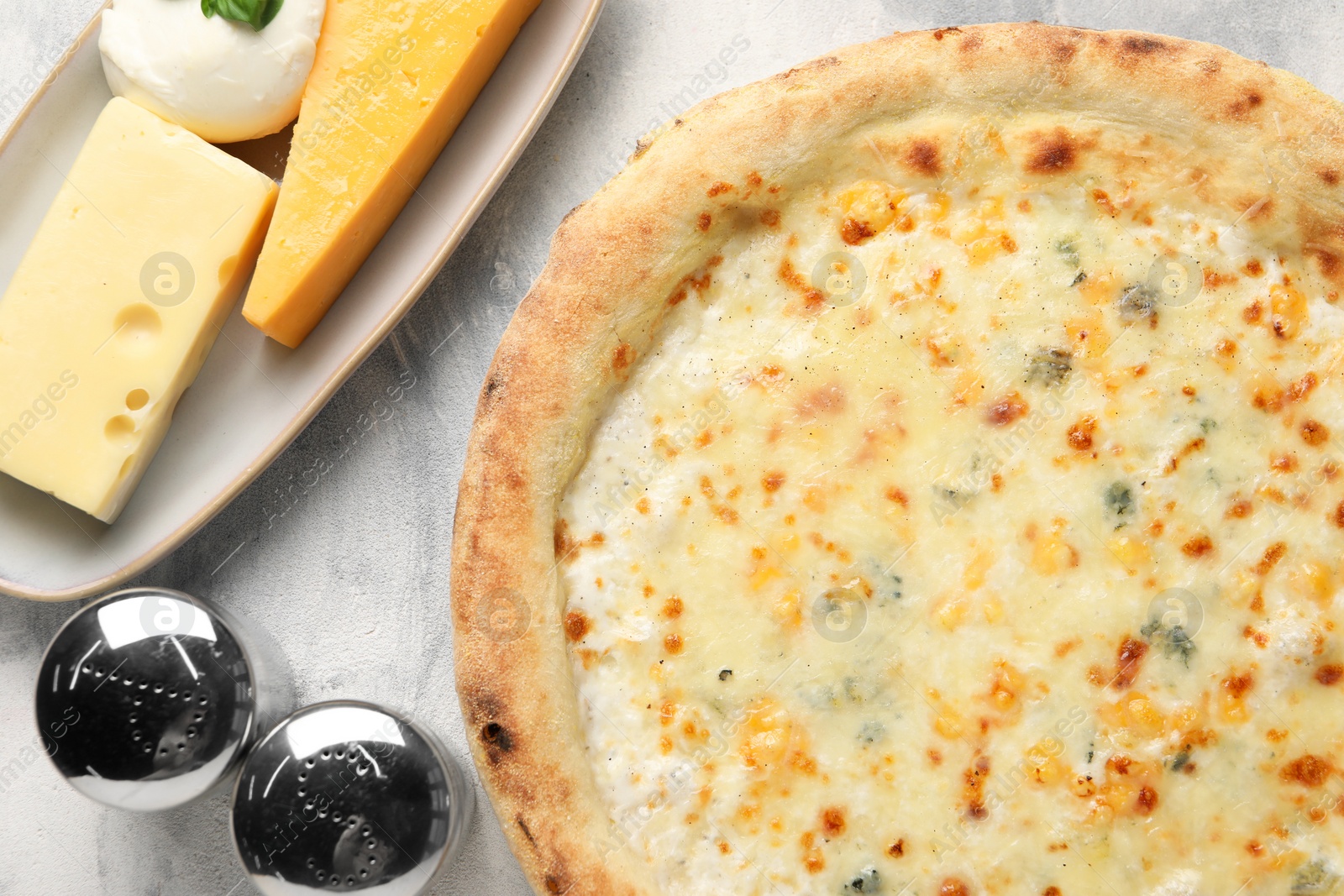 Photo of Delicious cheese pizza and different kinds of cheese on light grey textured table, flat lay