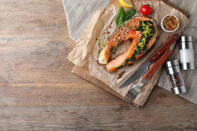 Photo of Tasty salmon with spinach served on wooden table, top view. Space for text