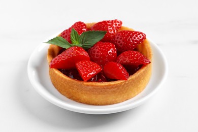 Tartlet with fresh strawberries on white table, closeup. Delicious dessert
